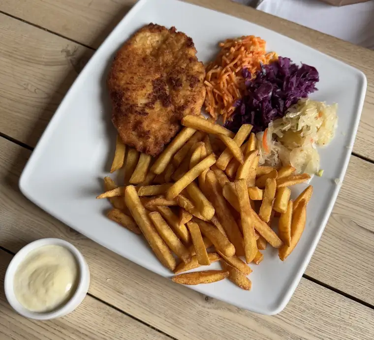 Kotlet z frytkami i surówkami na kwadratowym talerzu