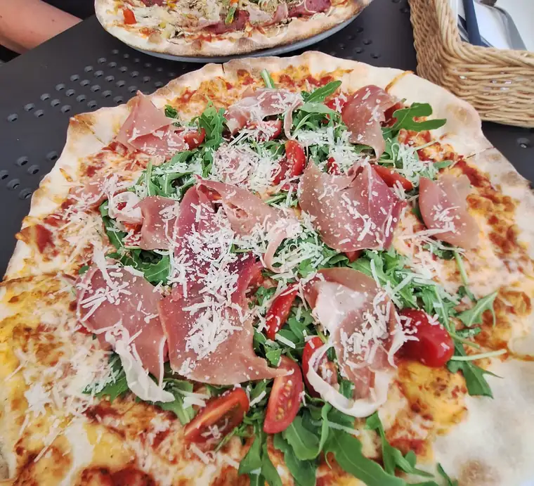 Pizza z szynką parmeńską, rukolą i parmezanem