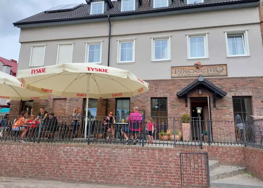 Budynek pizzerii z parasolami i ogródkiem przed wejściem